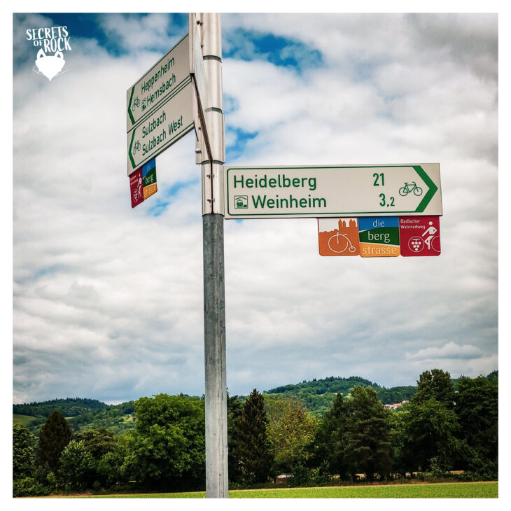Foto von einem Wegweiser mit Schildern in unterschiedliche Richtungen u.a. 21km nach Heidelberg